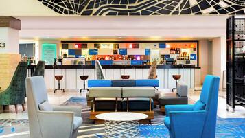 Um lobby moderno com assentos, área de bar e teto estampado.