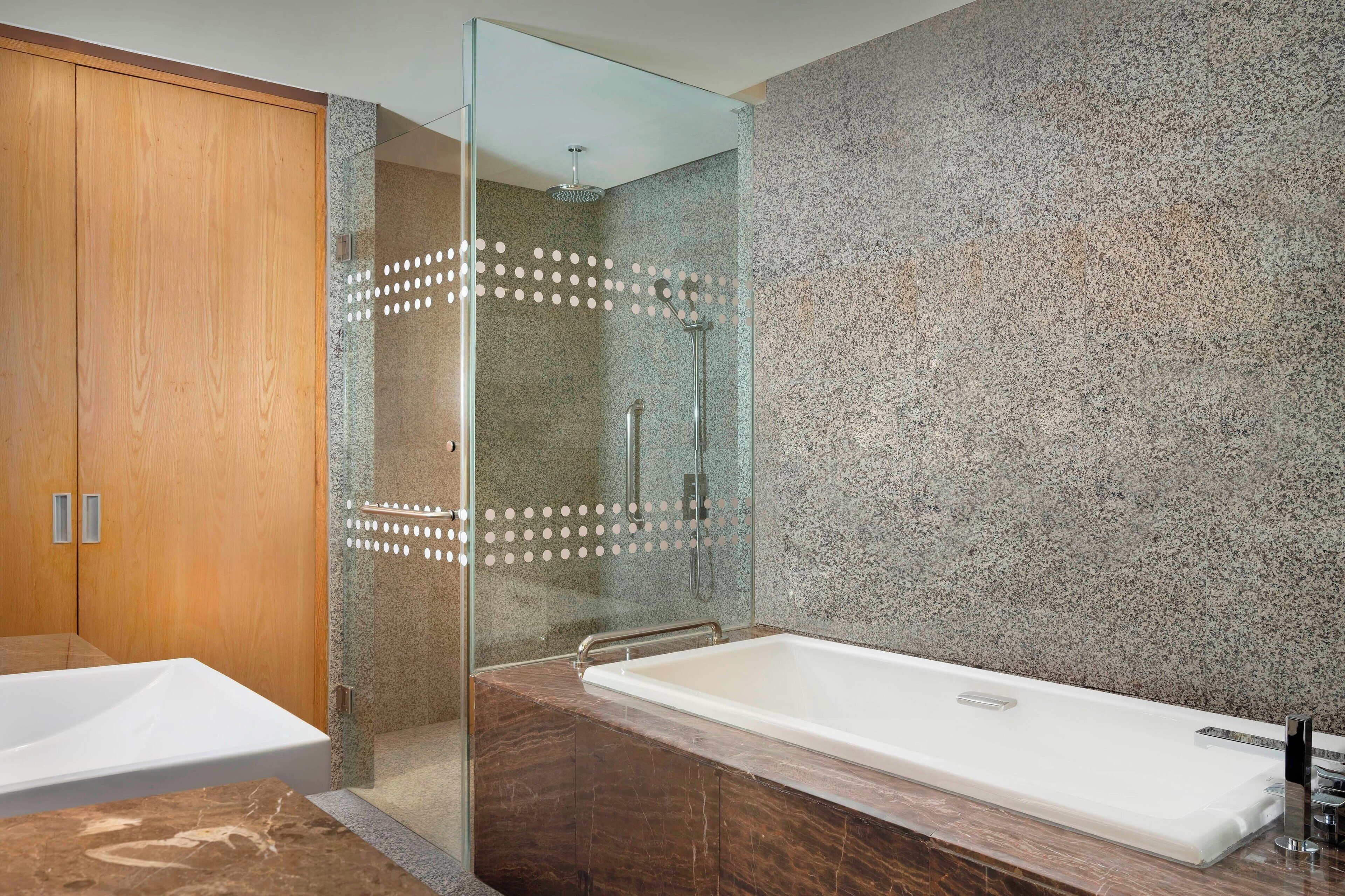 Ein modernes Badezimmer mit einer Duschkabine aus Glas, einem Holzschrank und einer Badewanne mit Marmorplatte.