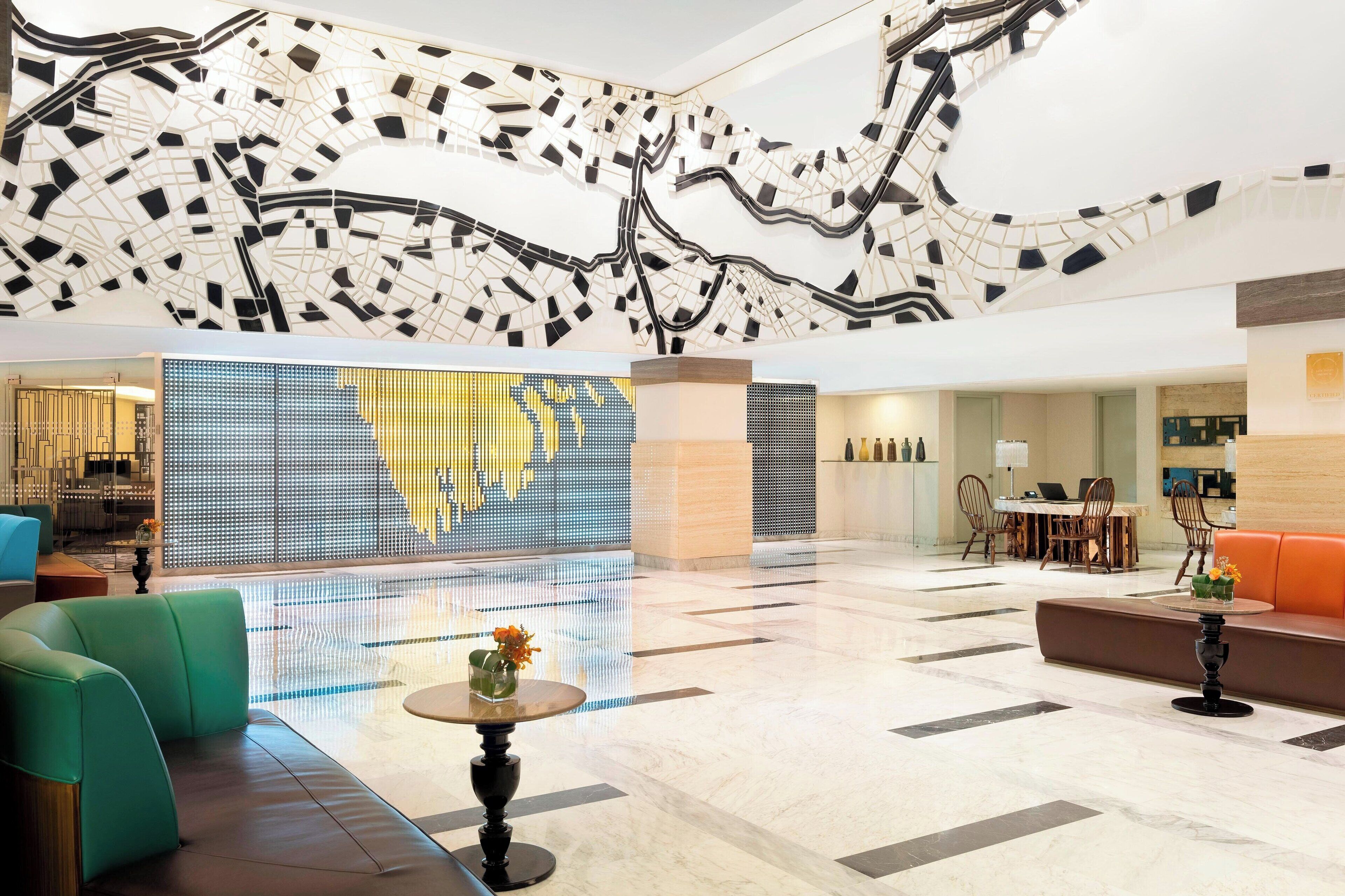 A spacious lobby with a modern design, featuring a large digital display, seating areas, and a unique ceiling artwork.