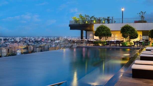 A rooftop pool with a city view, outdoor seating, and a glass balustrade. - Le Meridien Dhaka (Dhaka)