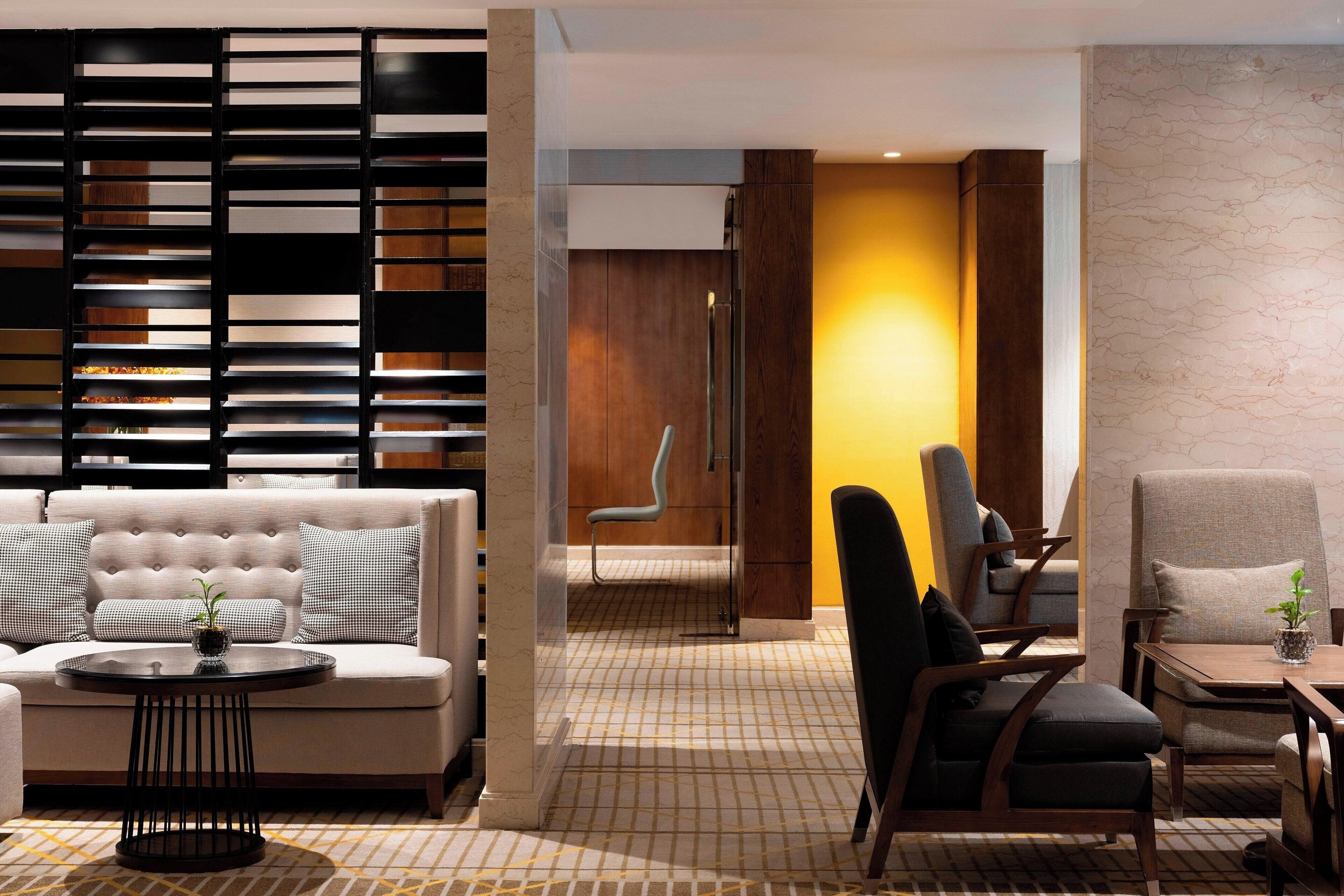 A modern hotel lobby with a sofa, chairs, a small table, and a patterned floor.