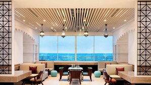 A spacious lounge area with a large table and chairs, a fireplace, and a view of the ocean. - Le Meridien Dhaka (Dhaka)