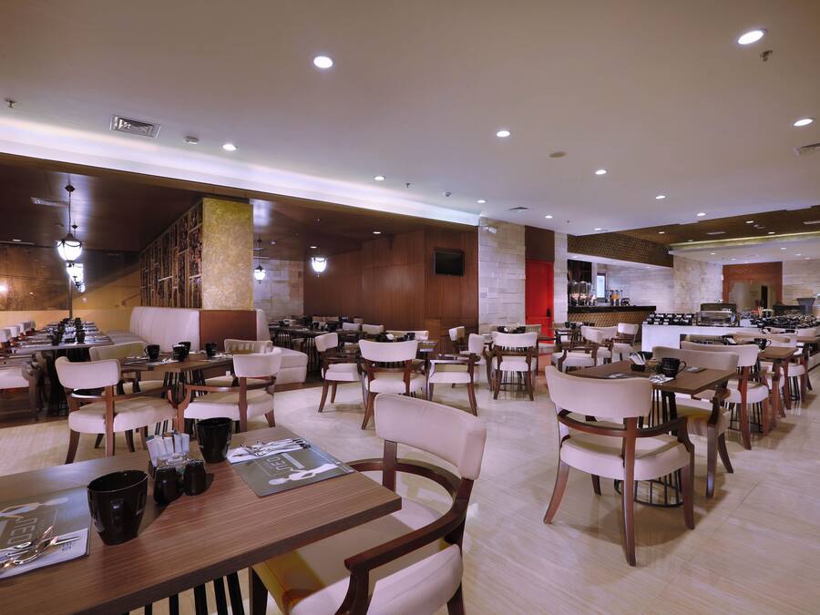 Um restaurante espaçoso com várias mesas e cadeiras, área de cozinha e design de interiores moderno.