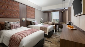 A hotel room with two beds, a dining table, and a TV. - The Alana Hotel & Conference Center Malioboro Yogyakarta by ASTON (Yogyakarta)