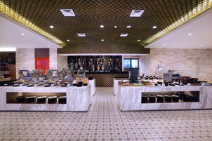 Un'area buffet con diverse stazioni di servizio, un pavimento decorato e un soffitto con illuminazione a incasso.