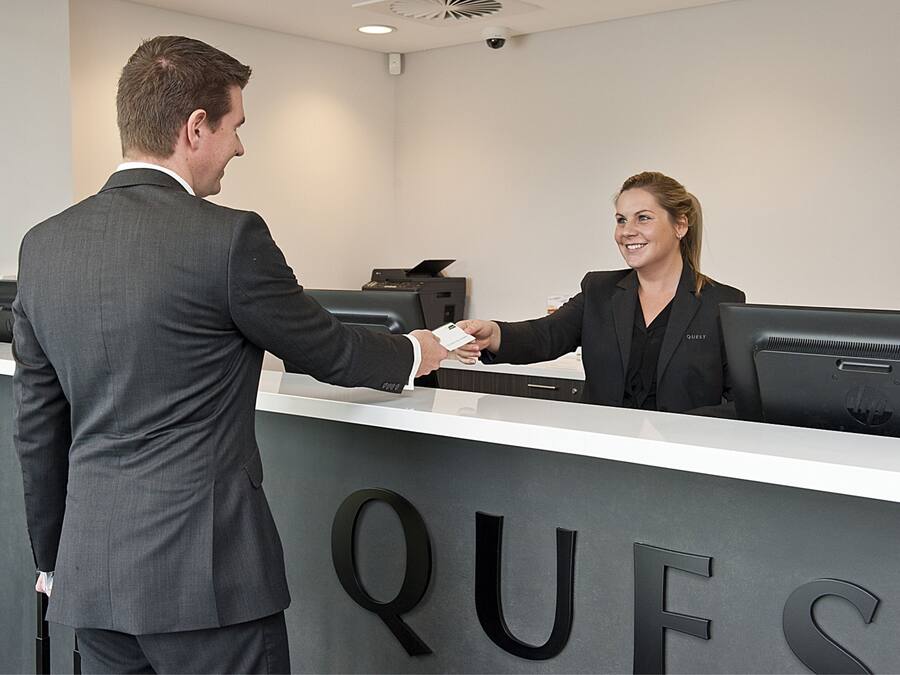 A reception desk with a man and a woman shaking hands.