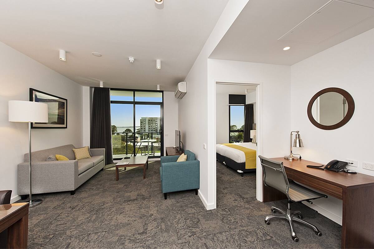 A hotel room with a sofa, armchair, desk, and a bed.