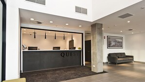 A reception area with a dark counter labeled "QUEST," a modern sofa, and a framed picture on the wall. - Quest Rockingham (Rockingham)