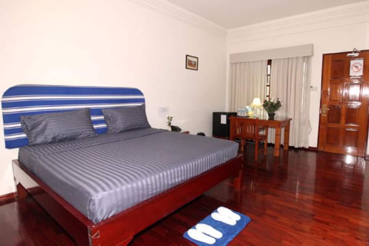 A bedroom with a bed, a desk, and a door.