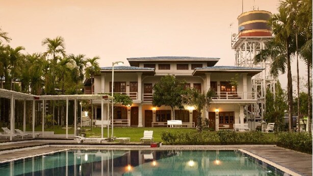 A hotel with a swimming pool, lounge area, and a water tower in the background. - Myanmar Life Hotel (Yangon)
