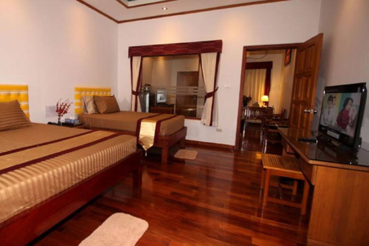 A hotel room with two beds, a wooden desk, a television, and a mirror.