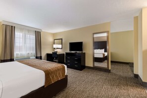 A hotel room with a large bed, a flat-screen TV, a desk with a chair, a mirror, and a window with curtains. - Comfort Inn Yankton SD (Yankton)