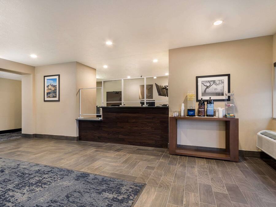 A reception area with a wooden reception desk, a framed picture on the wall, and a standing fan.