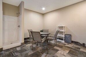 A bathroom with a bathtub, a shower, and a toilet. There is a small table with chairs and a shelf with toiletries. - Comfort Inn Yankton SD (Yankton)