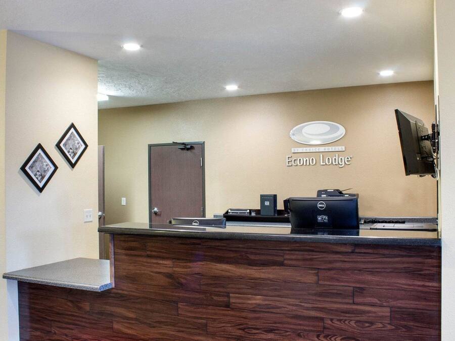 A hotel reception desk with a wooden counter, a Dell computer, and a sign for Econo Lodge.