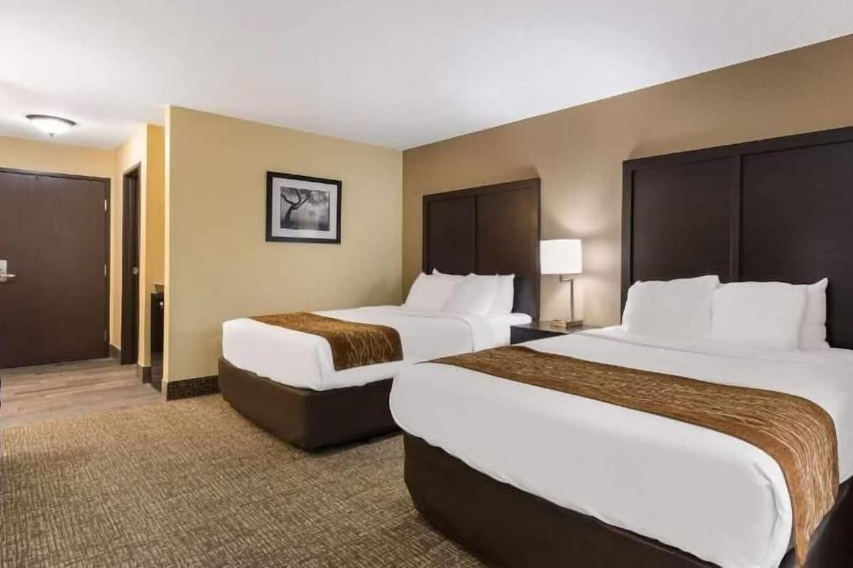 A hotel room with two beds, a framed picture on the wall, and a carpeted floor.