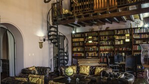 Una biblioteca con sofás de cuero, un globo terráqueo y un piano.