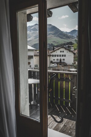 Vista desde un balcón con cubierta de madera y baranda metálica, sobre un paisaje montañoso y un edificio con el letrero "Hotel de la Plagne".