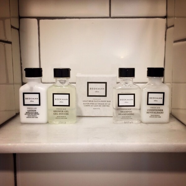 A shelf with four bottles of Beekman 1801 products: Fresh Air Lotion, Shower Gel, Goat Milk Face & Body Bar, and Conditioner Revitalisant.