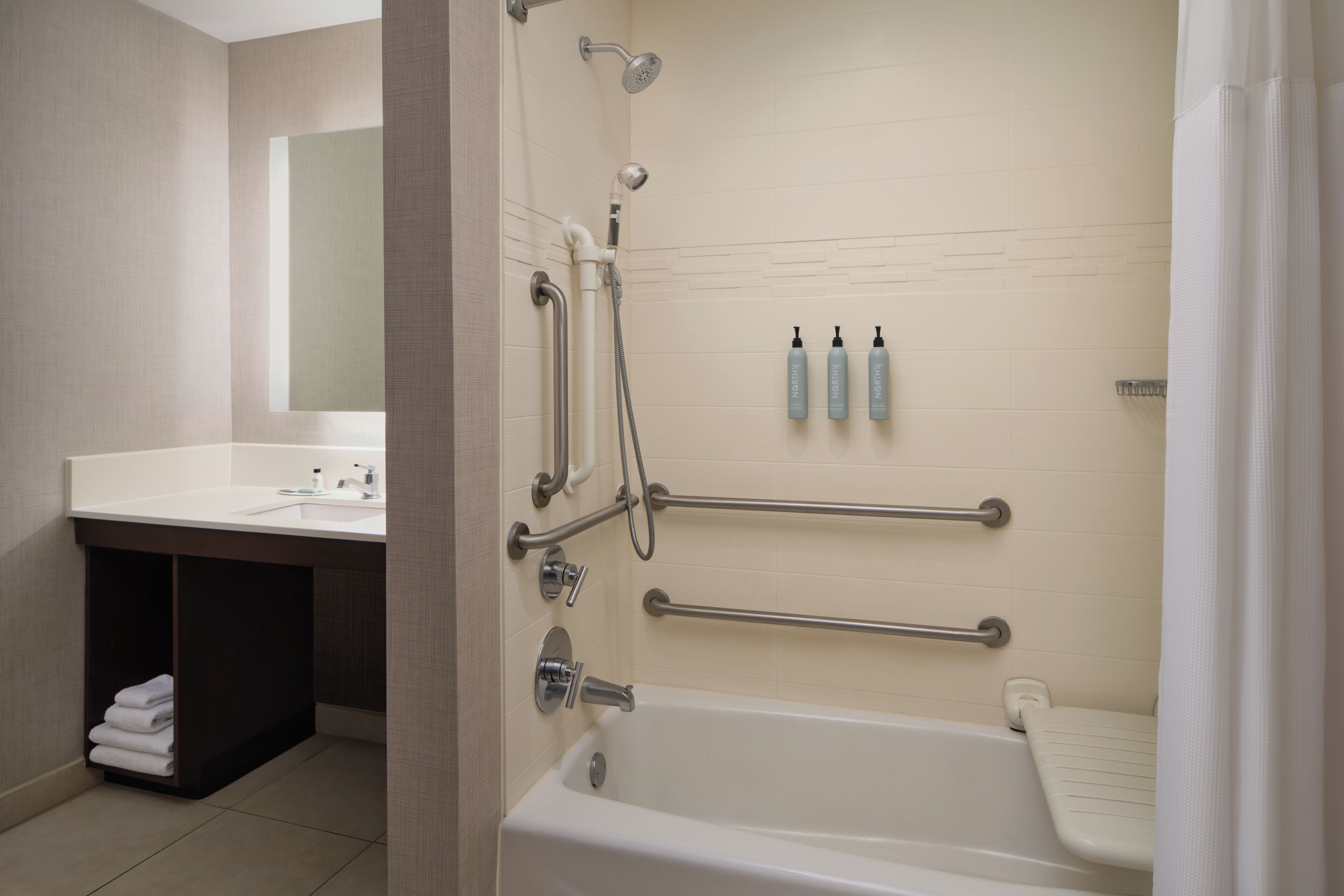 A bathroom with a bathtub, a sink, and a mirror.