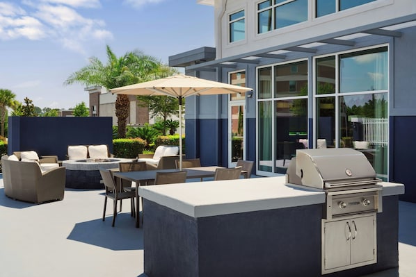 An outdoor patio with a barbecue grill, seating area, and a large umbrella.
