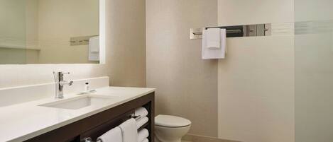 A modern bathroom with a large mirror, a sink, a toilet, and a towel rack.