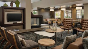 Eine geräumige Lobby mit Flachbildfernseher, Kamin, Ledersesseln und einem Couchtisch.
