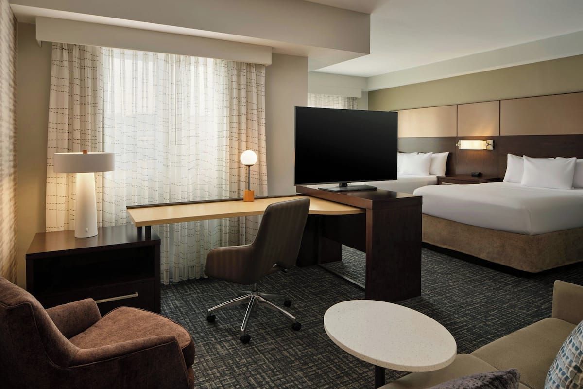 Een hotelkamer met een bed, bureau, stoel, televisie en een klein tafeltje.