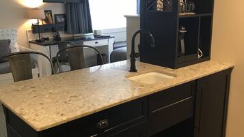 A compact kitchen with dark cabinetry, a granite countertop, and a built-in sink.