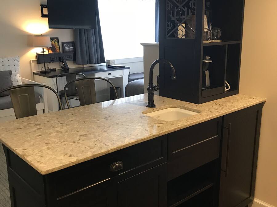 A compact kitchen with dark cabinetry, a granite countertop, and a built-in sink.
