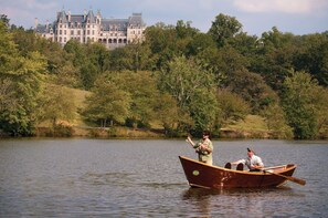 Ein hölzernes Boot auf einem ruhigen See mit einem großen Gebäude im Hintergrund.