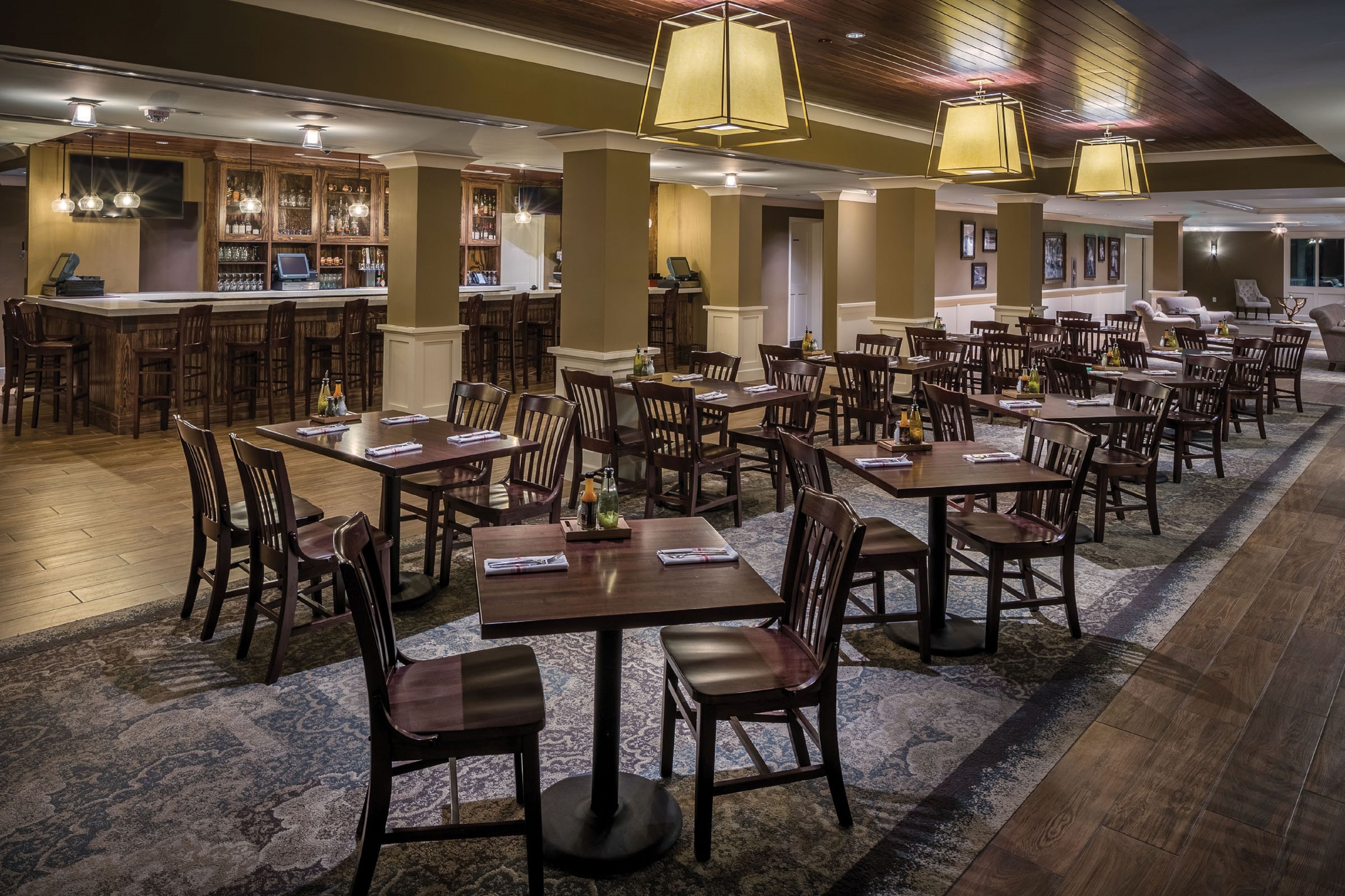 Un restaurante con varias mesas y sillas, una zona de bar y un área de estar con sofás y sillones.