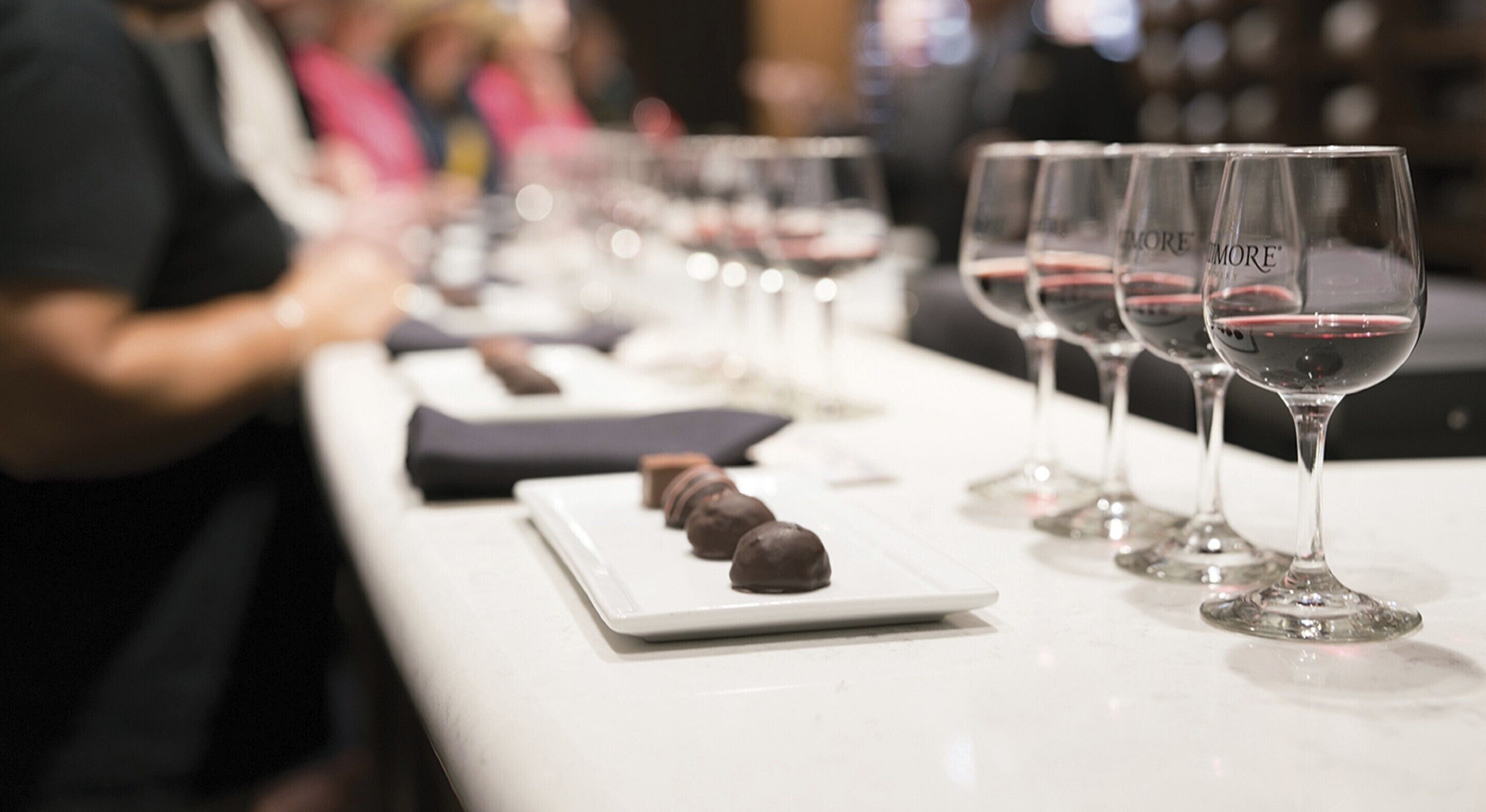 A tasting event with wine glasses and chocolate samples on a table.