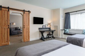 A hotel room with a bed, a desk, a TV, and a window with curtains.