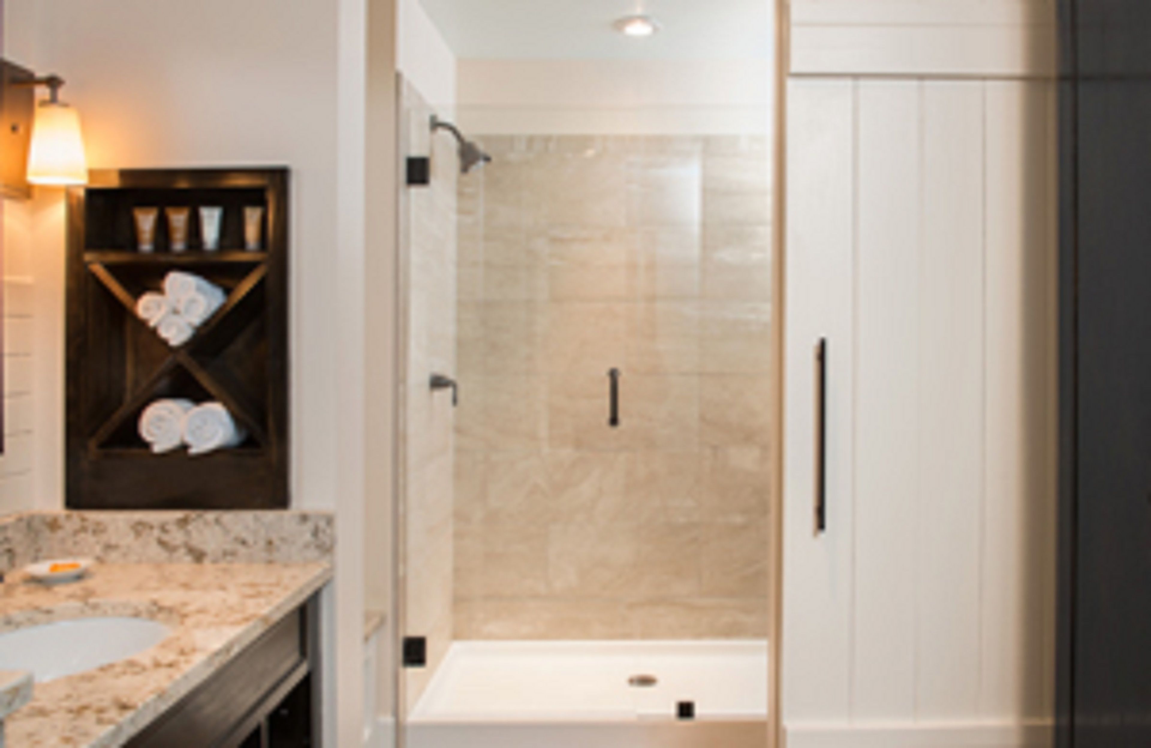 A modern bathroom with a marble countertop, a glass shower enclosure, and a towel rack with towels.
