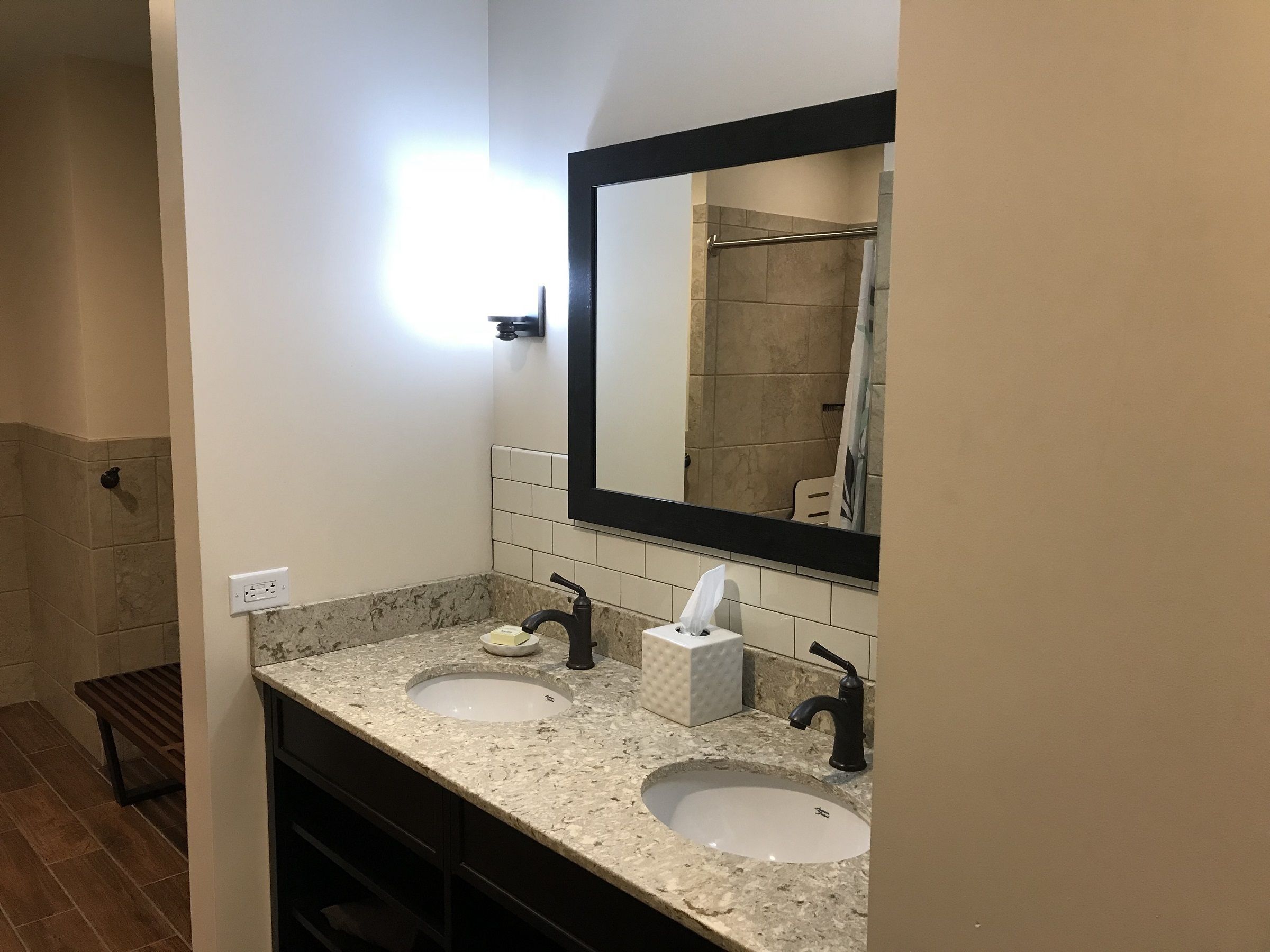 Un baño con dos lavamanos, un espejo y un perchero para toallas.