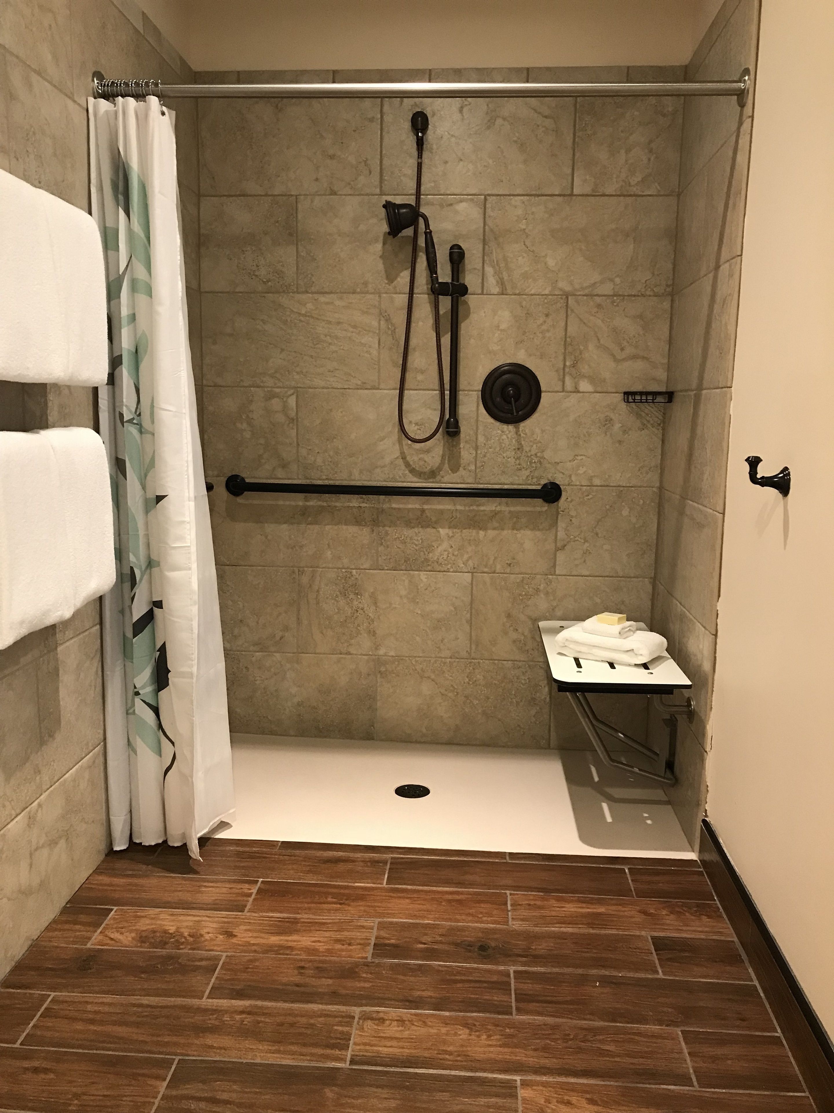 A shower area with a grab bar, a small bench, and a towel rack.