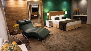 A modern bedroom with a bed, a chaise lounge, a small table with a vase, and a large fluffy rug. - Alfa Hotel (Vicosa)