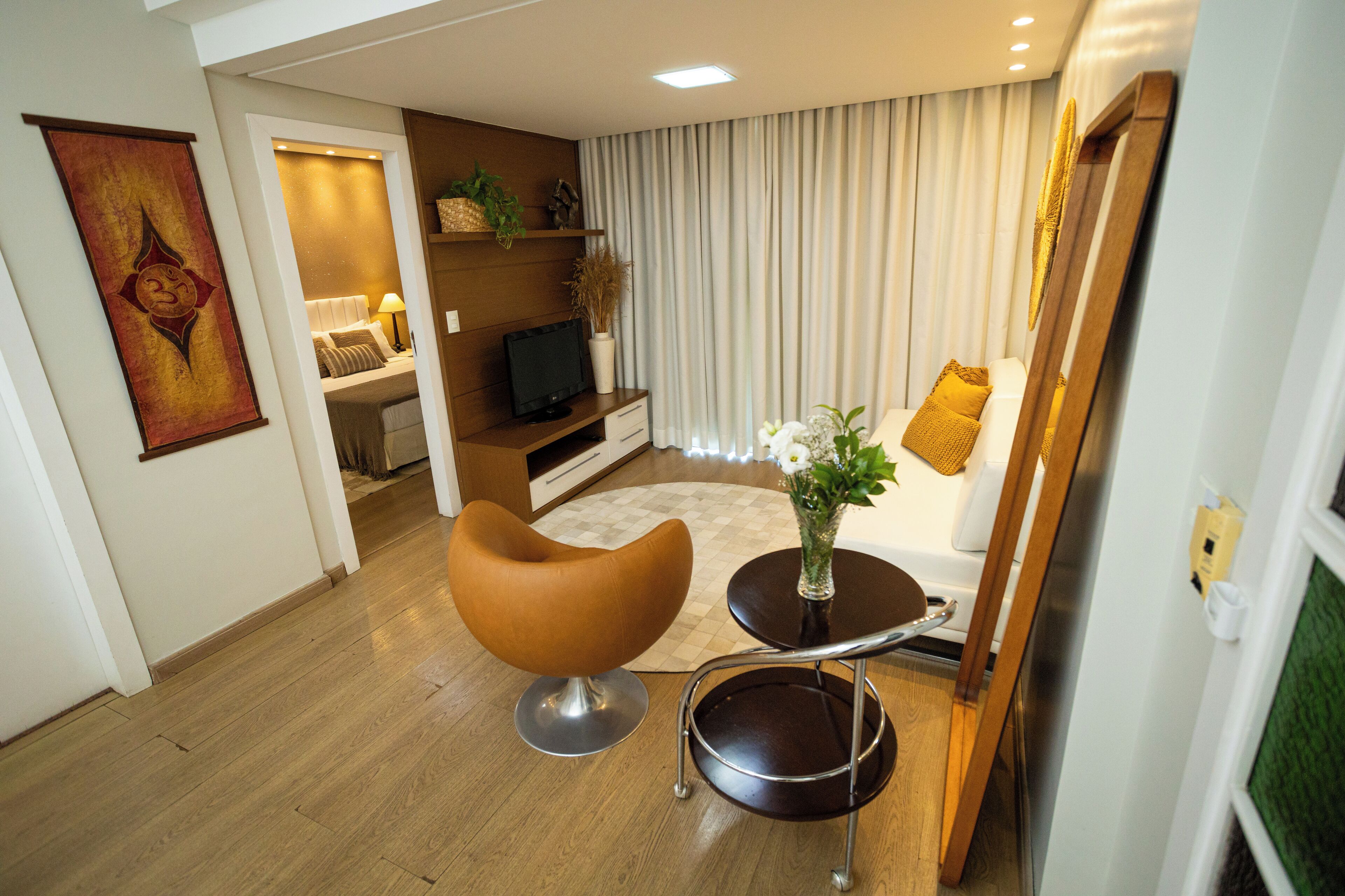 Ein modernes Wohnzimmer mit einem braunen Sessel, einem kleinen runden Tisch und einem Fernseher auf einem Holzboden.