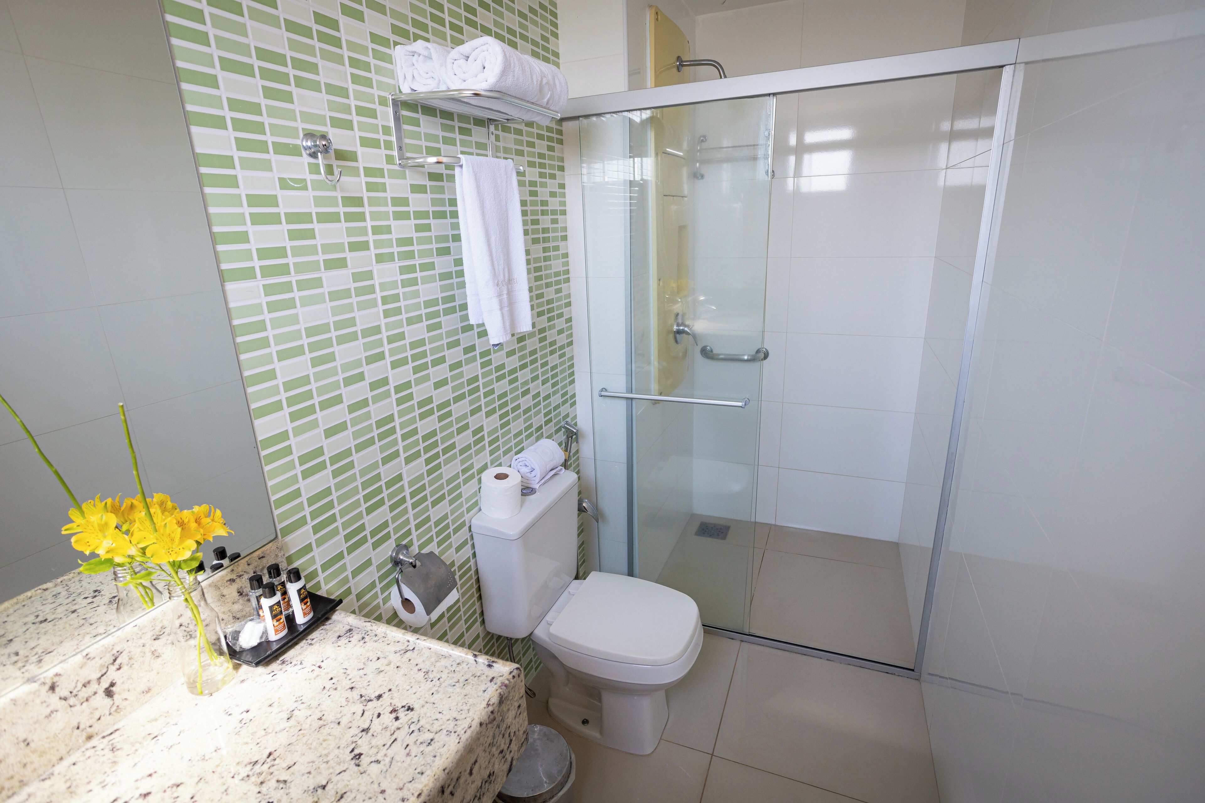 A bathroom with a glass-enclosed shower, a toilet, and a sink with a marble countertop.