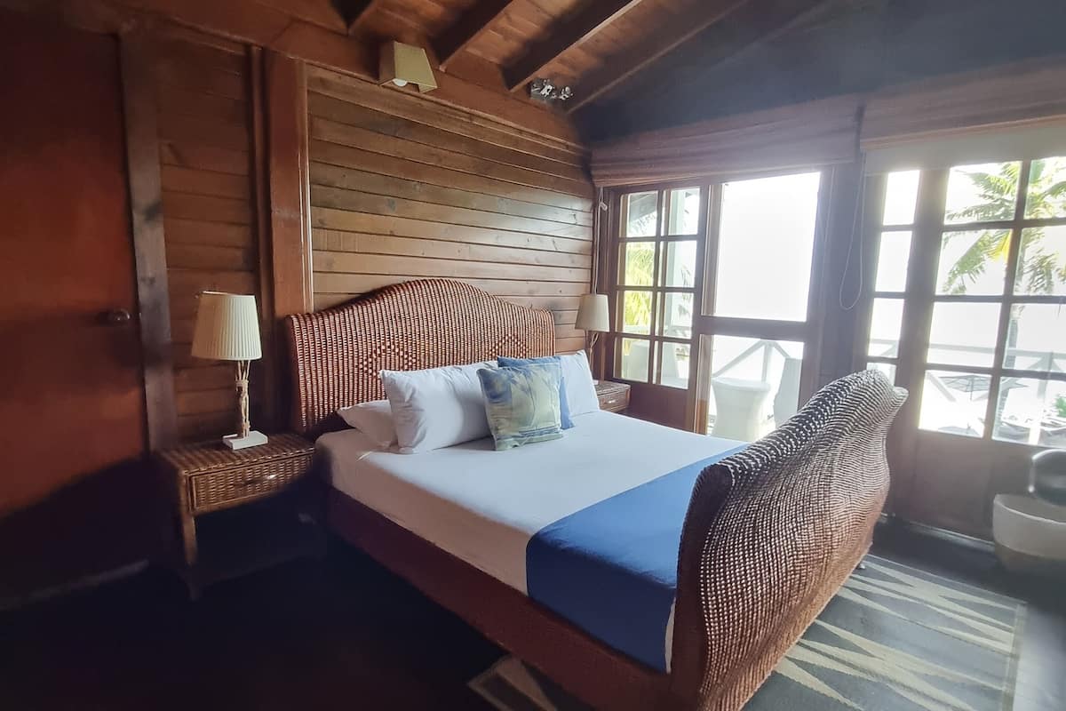 A wooden room with a bed, a ceiling fan, and large windows.