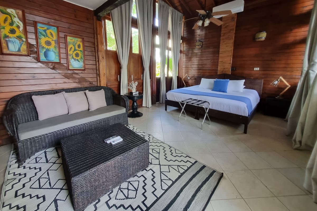 A wooden cabin-style room with a bed, sofa, and a small table.