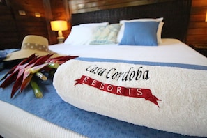 Una cama con una toalla blanca que dice "casa Cordoba RESORTS" y un cojín azul.