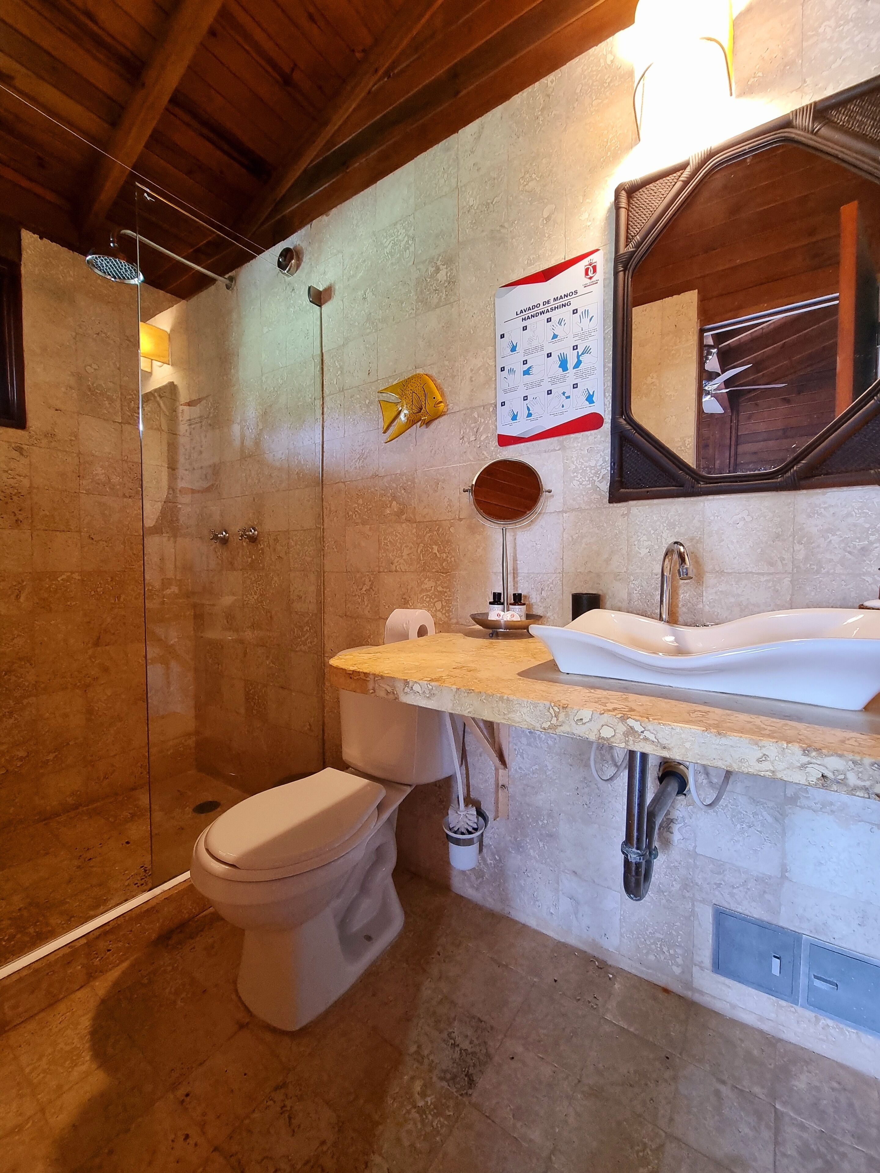 Une salle de bain avec une douche à parois de verre, des toilettes et un lavabo avec un miroir au-dessus.