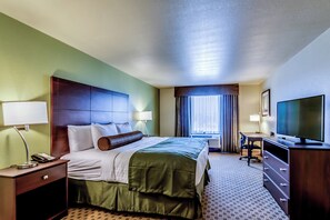 A hotel room with a bed, a desk, a television, and a window with curtains.