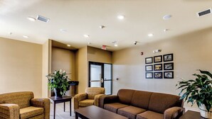 A lobby with a brown sofa, two armchairs, a coffee table, and potted plants. - Cobblestone Inn & Suites - Waverly (Waverly)