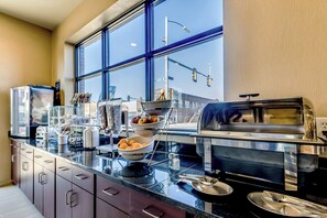A modern kitchen with a large window, stainless steel appliances, and a variety of bowls and utensils on the counter.