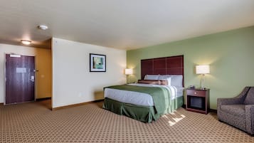 A hotel room with a bed, two bedside lamps, a chair, and a door.