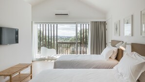 Un dormitorio moderno con dos camas, un televisor y un balcón con vistas al campo.