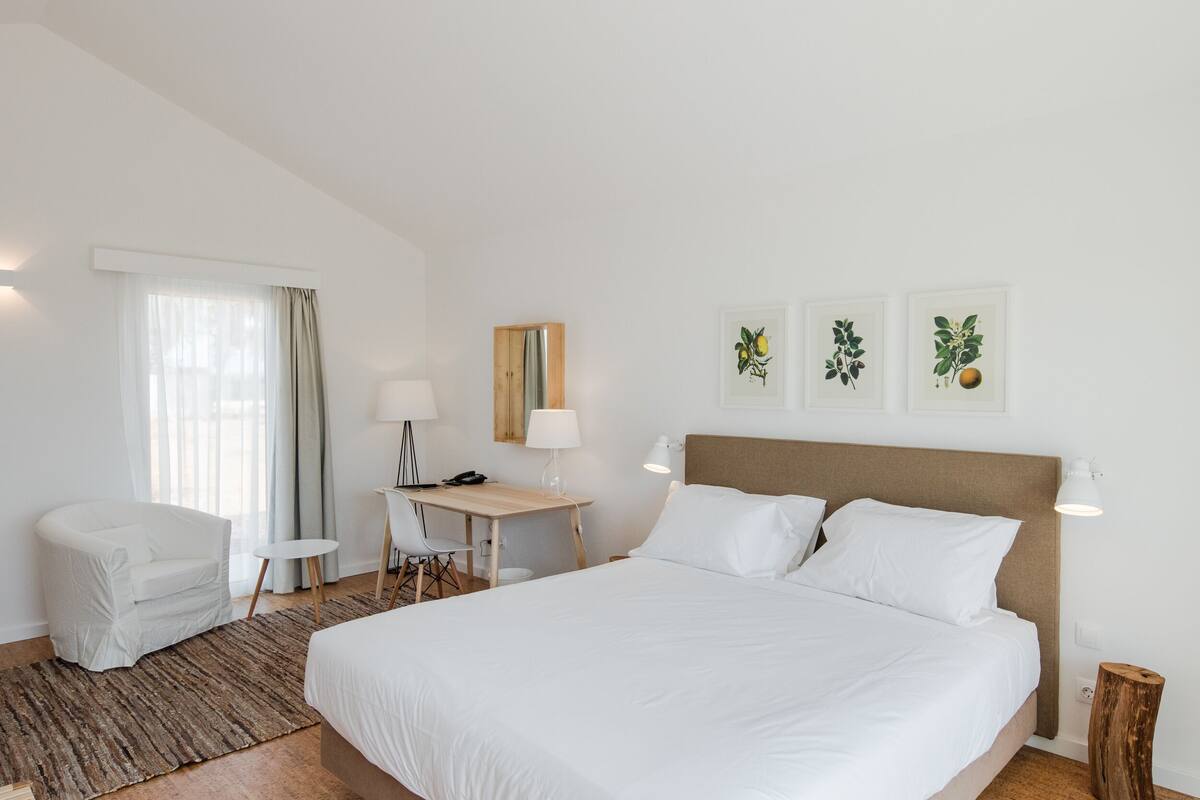 Una habitación de hotel con una cama grande, un escritorio, una silla y una mesita.